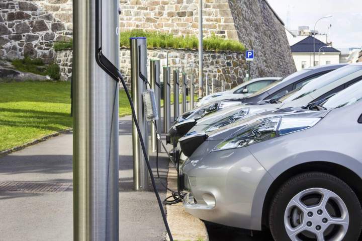 Plusieurs bornes de recharge pour véhicules électriques installées sur le parking dune entreprise moderne, avec des voitures en charge, illustrant une solution professionnelle.
