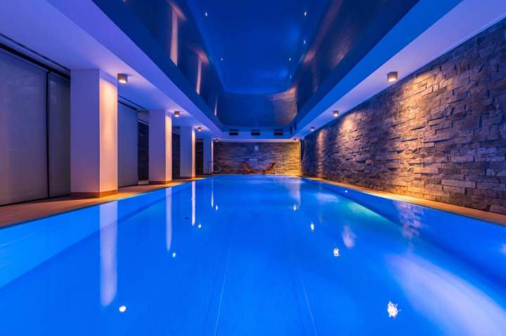 Piscine éclairée par des lumières LED subaquatiques multicolores la nuit, créant une atmosphère relaxante et moderne, avec des reflets sur leau.